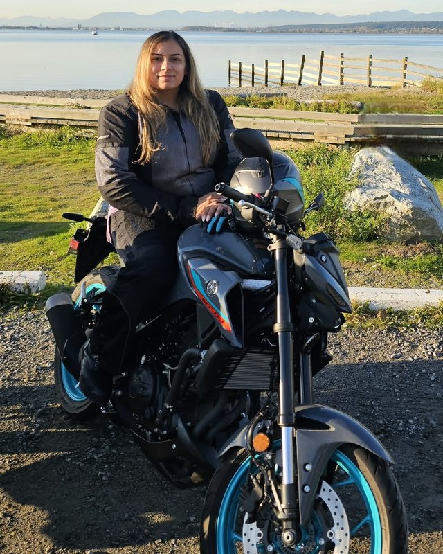 Jessica seated on her motorcycle beside the water